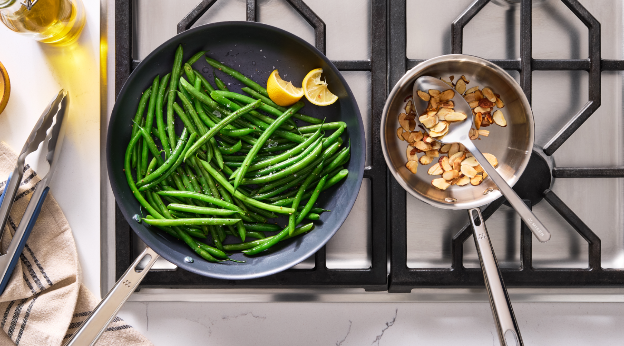 Sautéed green beans and toasted almonds on a gas stovetop